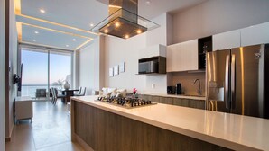 A modern kitchen with a central island, stainless steel appliances, and a view to the outside.