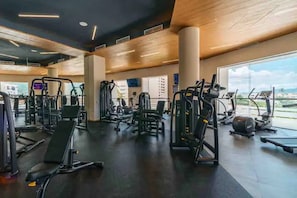 Un gimnasio con equipos de ejercicio variados, amplias ventanas y un diseño interior moderno.