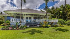 A two-story house with a covered porch, surrounded by lush tropical landscaping. - Hawaii Life Rental Presents Makana Nui (Hanalei)