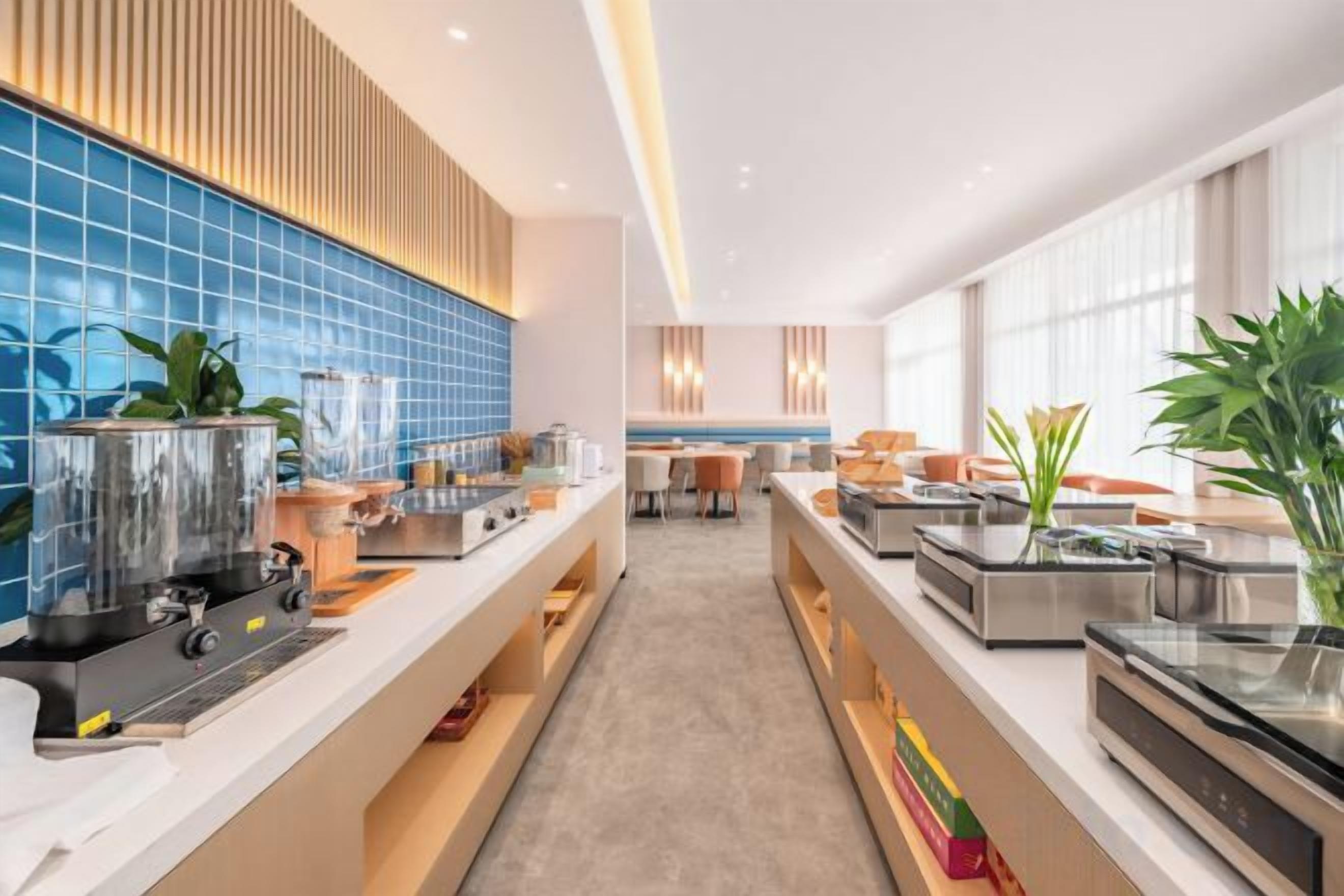 A modern kitchen with stainless steel appliances, a blue tiled backsplash, and a long counter.