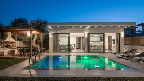 Ett modernt hus med en swimmingpool, utomhusmöbler och en uteplats.