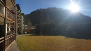 A building with a balcony overlooking a grassy area and a mountain in the background.
