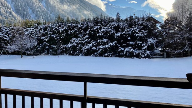 A snow-covered landscape with a wooden deck in the foreground.