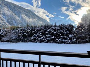 Un paysage enneigé avec une terrasse en bois au premier plan.
