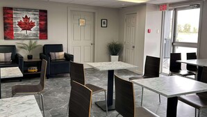 A modern dining area with marble tables and chairs, a Canadian flag artwork, and a restroom sign.