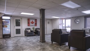 A lobby with a marble floor, seating area, a vending machine, and a clock on the wall.