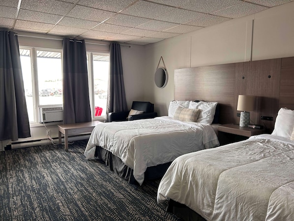 Une chambre d’hôtel avec deux lits, un bureau, une chaise et une fenêtre avec des rideaux.