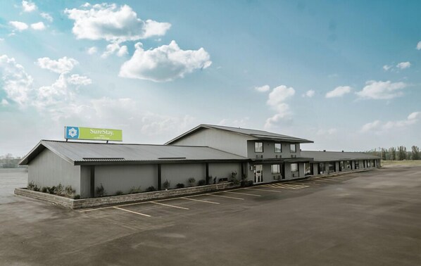 A SureStay hotel with a large parking lot and a clear sky.