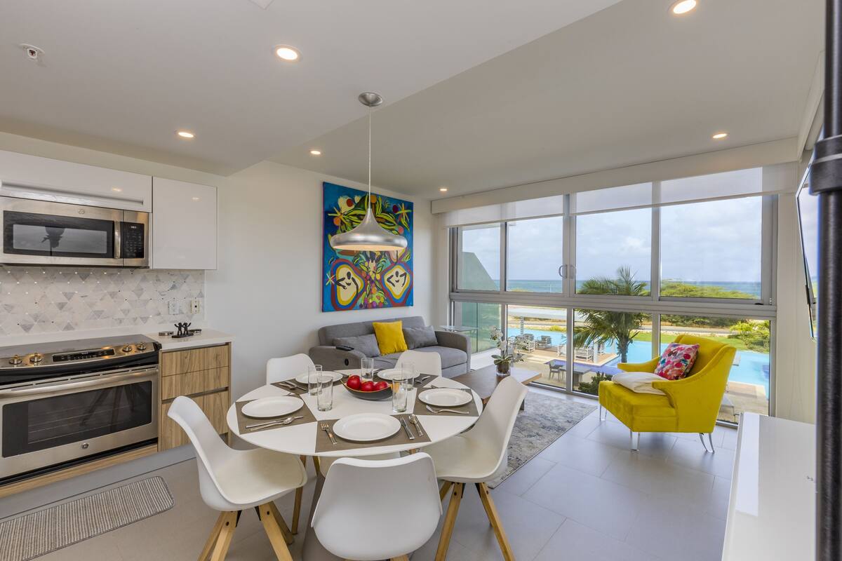 Una cocina moderna con comedor, ventanas amplias y vistas a una piscina.