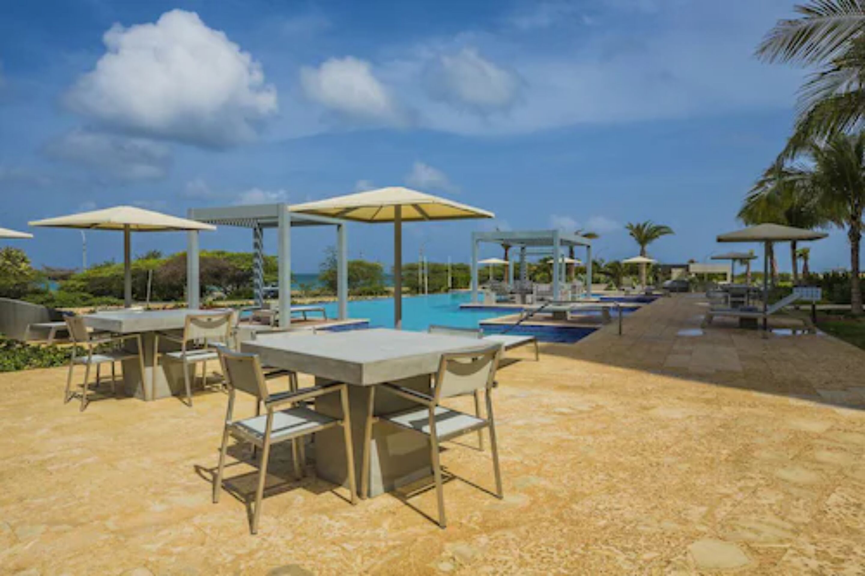 Zona junto a la piscina con mobiliario exterior y sombrillas.