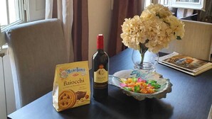 A dining table with a package of biscotti, a bottle of Chianti wine, and a vase with flowers. - Apartment Ponte Vecchio (Firenze)
