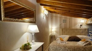 A bedroom with a bed, bedside table, lamp, and wall-mounted light fixture. - Apartment Ponte Vecchio (Firenze)