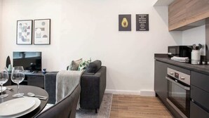 A modern living space with a dining area, sofa, kitchen, and artwork on the walls.