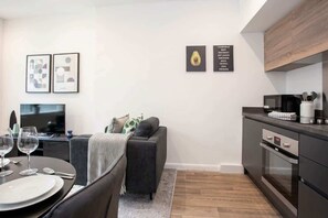 A modern living space with a dining area, sofa, kitchen, and artwork on the walls. - Stylish 2BR Bolton Apt Easy Transport Links (Bolton)