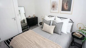 A bedroom with a bed, bedside tables, a wardrobe, and two framed pictures on the wall.