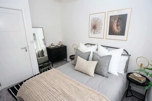 A bedroom with a bed, bedside tables, a wardrobe, and two framed pictures on the wall. - Stylish 2BR Bolton Apt Easy Transport Links (Bolton)