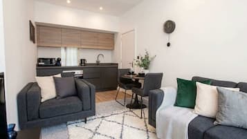 A modern living room with a sofa, a coffee table, and a dining area with chairs and a table.