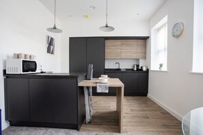 A modern kitchen with dark cabinetry, a wooden island, and pendant lighting.