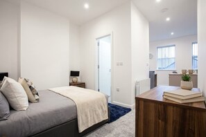 A bedroom with a bed, bedside tables, a desk, and a window.