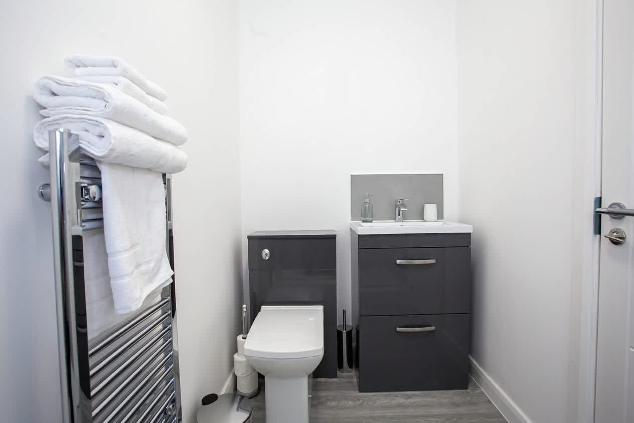 A compact bathroom with a toilet, a sink, and a towel rack.