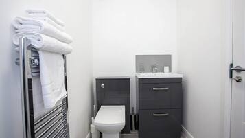 A compact bathroom with a toilet, a sink, and a towel rack.