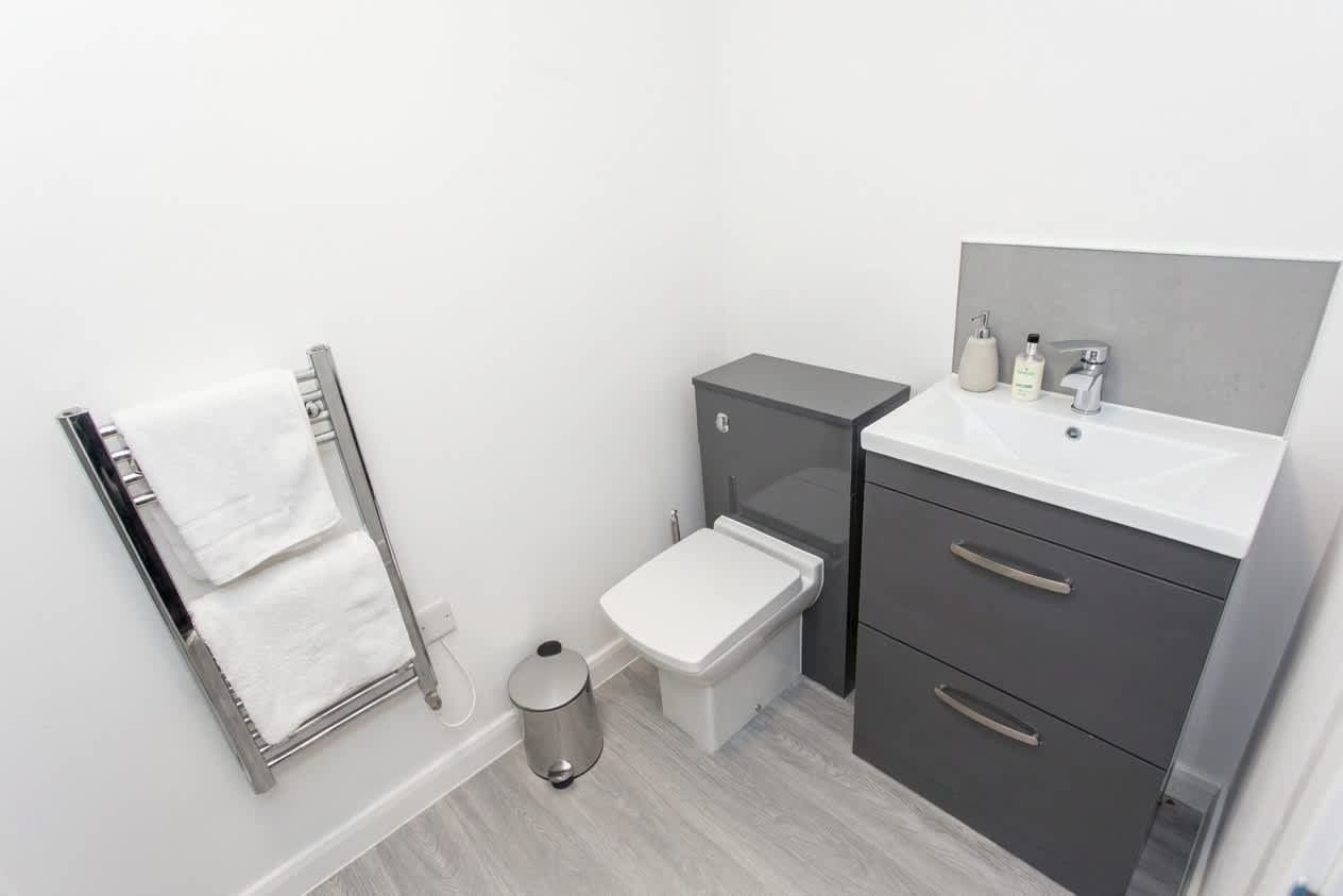Moderni kylpyhuone, jossa on wc, pesuallas ja pyyheteline.