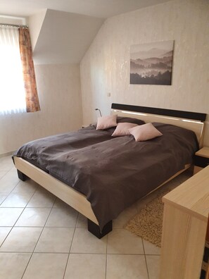 A bedroom with a bed, a nightstand, a lamp, and a painting on the wall.