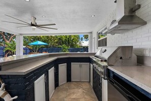 A kitchen with a built-in grill, white cabinets, and a ceiling fan.