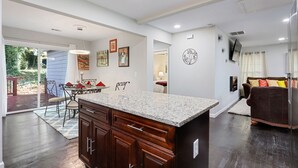 Una cocina moderna con una isla grande, armarios de madera y un comedor con mesa y sillas.