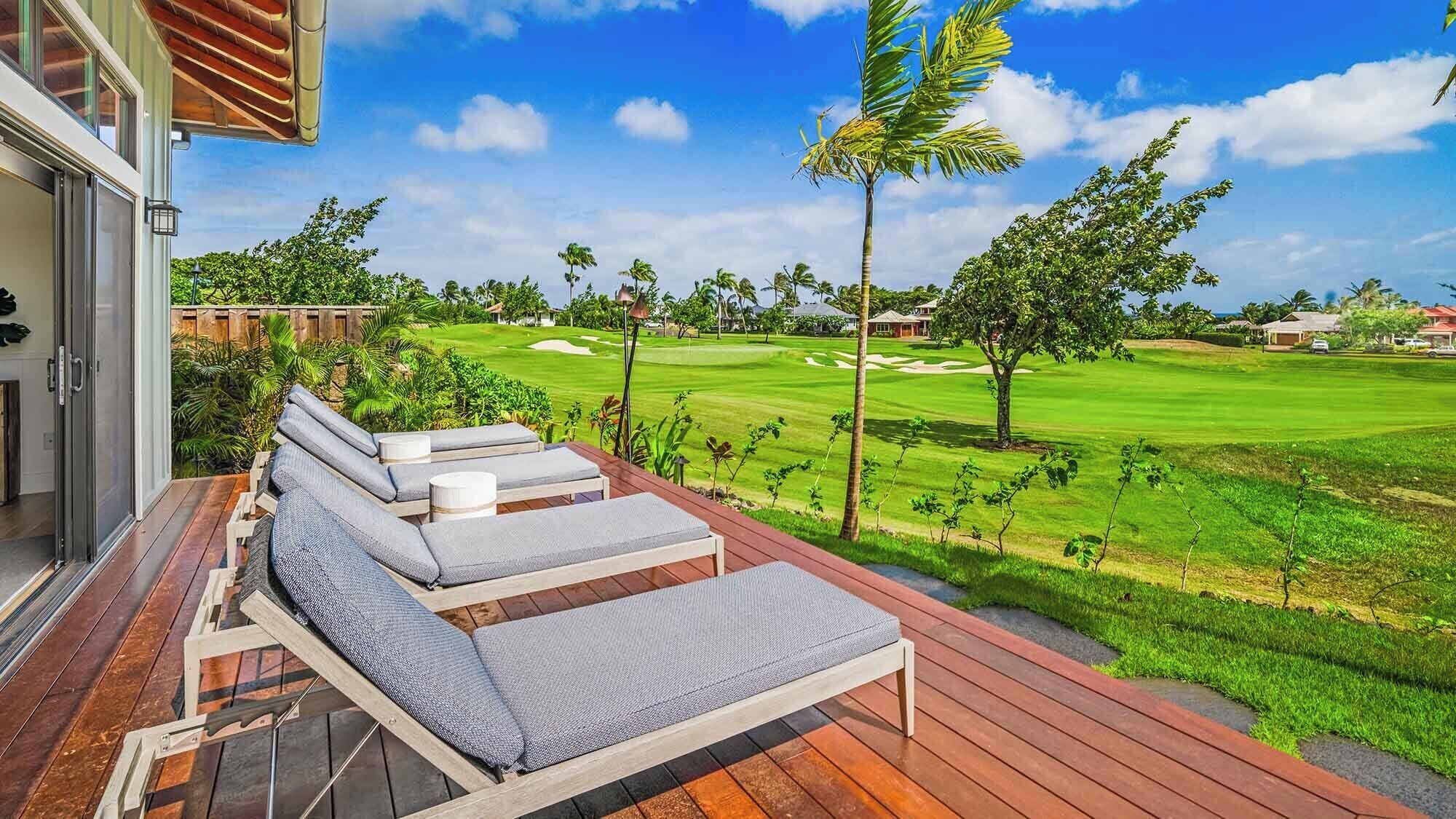 A deck with lounge chairs overlooking a golf course.
