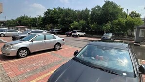 A parking lot with several cars parked, a small building, and trees in the background. - Jinjiang Inn (Tianjin Gangguan Company) (Tianjin)