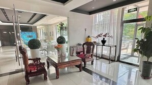 A modern lobby with a glass partition, wooden chairs, a glass coffee table, and potted plants. - Jinjiang Inn (Tianjin Gangguan Company) (Tianjin)
