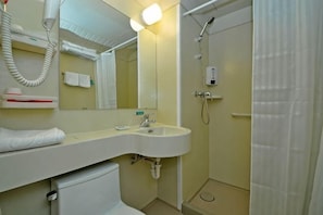 Un baño con lavamanos, espejo, toallero y ducha.