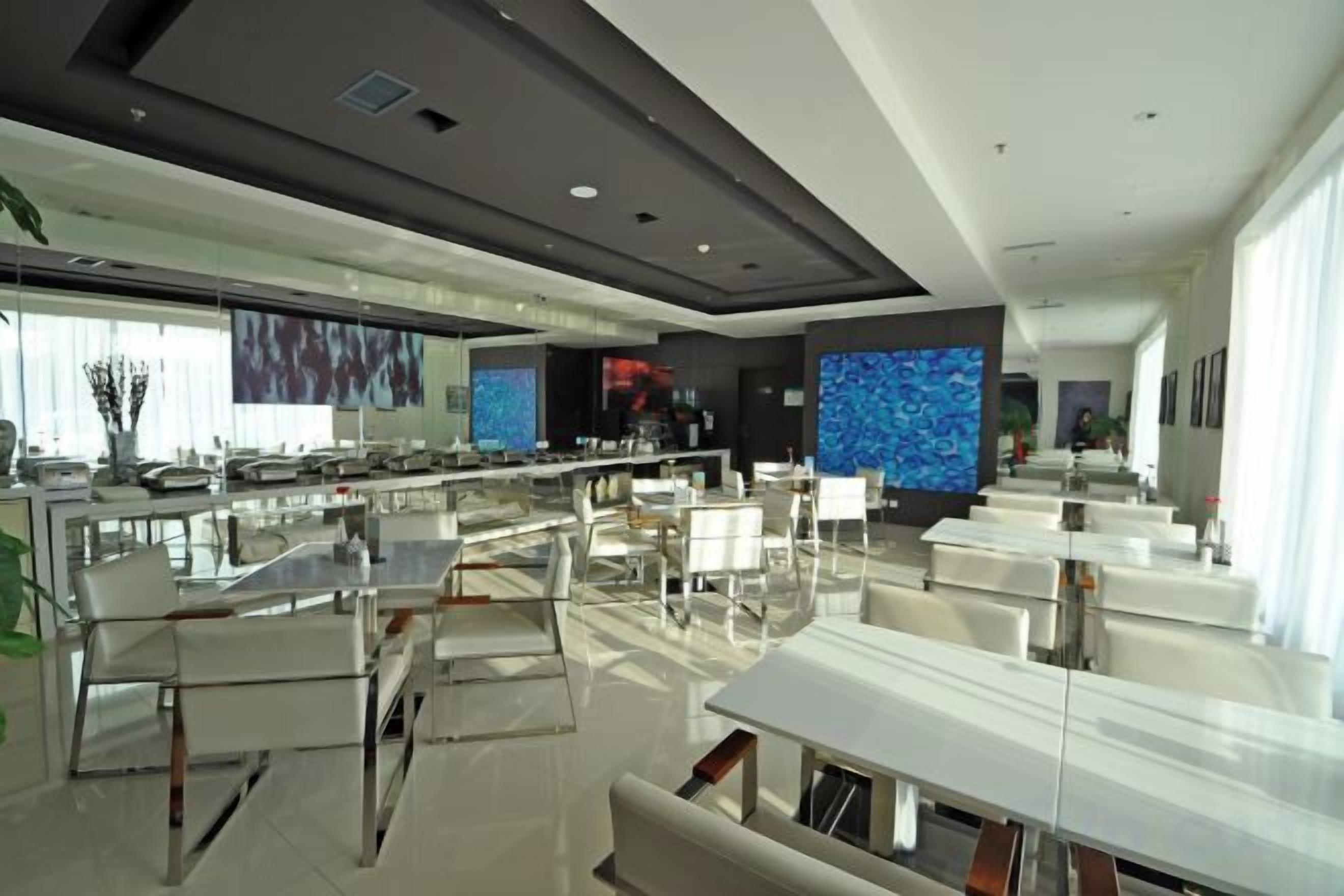 A modern hotel lobby with a bar area, seating, and a large digital screen.