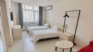 A hotel room with two beds, a round table, a red sofa, a mirror, and a radiator. - Jinjiang Inn (Tianjin Gangguan Company) (Tianjin)