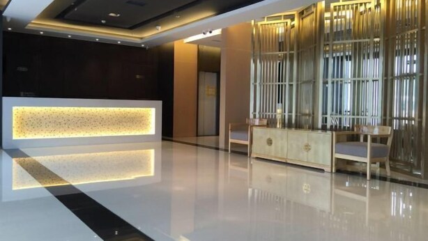 A modern lobby with a reception desk, a seating area with a wooden cabinet, and a decorative wall with vertical elements. - Jinjiang Inn (Tianjin Gangguan Company) (Tianjin)