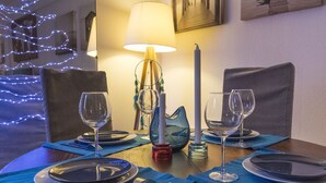Une table à manger dressée avec des assiettes, des couverts et des verres à vin, agrémentée d’une bougie et d’un joli pichet décoratif.