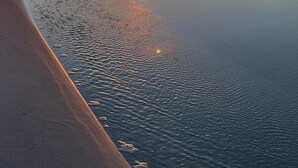 A beach at sunset with calm water reflecting the sky. - Modern Gulf-View Reno! Steps to Pool, Easy walk to Beach + Beach Gear & Wagon (Miramar Beach, Destin)