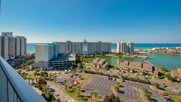 A high-rise hotel with multiple floors, a parking lot, and a view of the ocean. - Modern Gulf-View Reno! Steps to Pool, Easy walk to Beach + Beach Gear & Wagon (Miramar Beach, Destin)