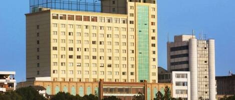 A multi-story hotel with a central courtyard, a prominent sign at the top, and a smaller building to the right.