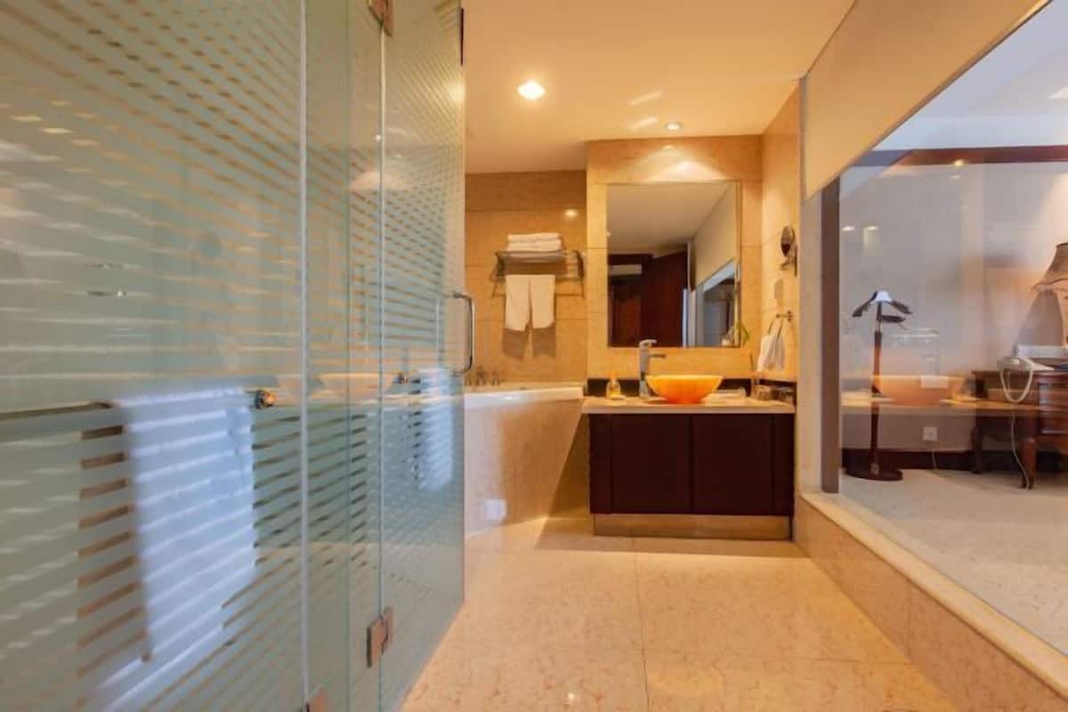 Un baño moderno con cabina de ducha de vidrio, un espejo grande, un lavabo y una cómoda.
