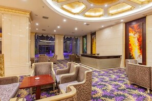 A hotel lobby with a reception desk, seating area, and a patterned carpet. - Jinyuan International Hotel (Yugan)