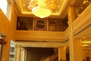 A grand lobby with a large chandelier, a staircase, and a decorative wall. - Jinyuan International Hotel (Yugan)