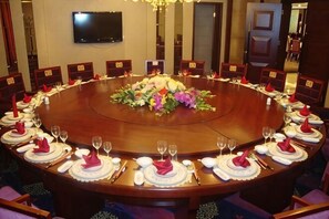 A conference room with a round table, chairs, and a floral centerpiece. - Jinyuan International Hotel (Yugan)