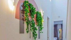 A hallway with a curved wall-mounted plant display, recessed lighting, and a wooden floor. - Belmont Music Row 4 Bed, Rooftop, 10 Minutes To DT | 24 Hour Hospitality Team, Perfect for Groups, 7.5 Miles to Airport (Nashville)