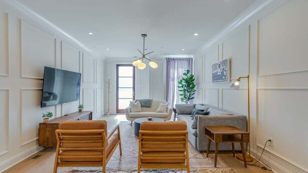 A spacious living room with a flat-screen TV, wooden furniture, and a large window. - Belmont Music Row 4 Bed, Rooftop, 10 Minutes To DT | 24 Hour Hospitality Team, Perfect for Groups, 7.5 Miles to Airport (Nashville)