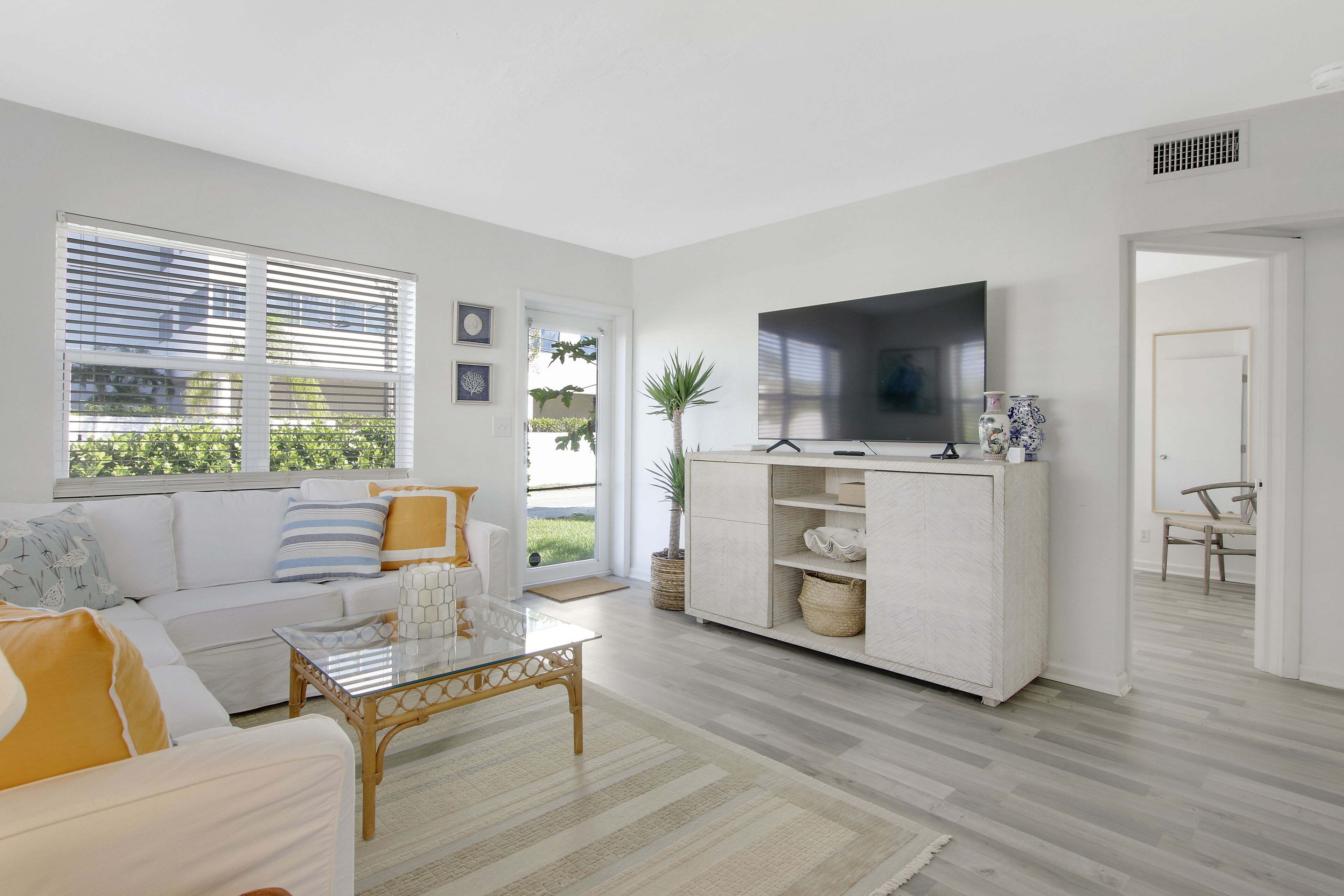 A modern living room with a sofa, coffee table, TV, and a large window with blinds.