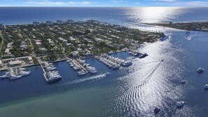 Vue aérienne d’une marina où sont amarrés de nombreux yachts, entourée de bâtiments résidentiels et d’un paysage côtier.