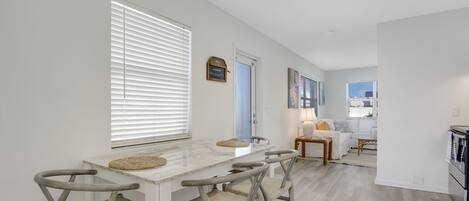 A modern kitchen with a marble countertop, four wooden chairs, and a dining table.
