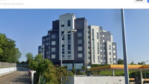 En bygning med flere etager i moderne arkitektur, med en blanding af mørke og lyse facader og et fladt tag.